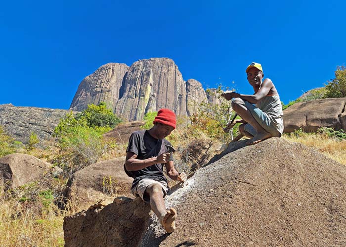 zwei Wegebauer beim Knochenjob mit einem primitiven Handbohrmeissel; darüber der Gr. Tsaranoro zwei Wegebauer beim Knochenjob mit einem primitiven Handbohrmeissel; darüber der Gr. Tsaranoro