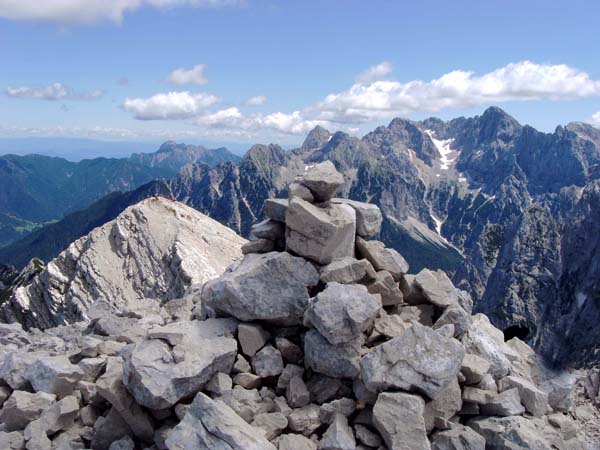 der Gipfelsteinmann auf der Velika Mojstrovka, dahinter die kleine Schwester und der Špik-Škrlatica-Zug, ganz hinten der Mittagskogel (Karawanken)