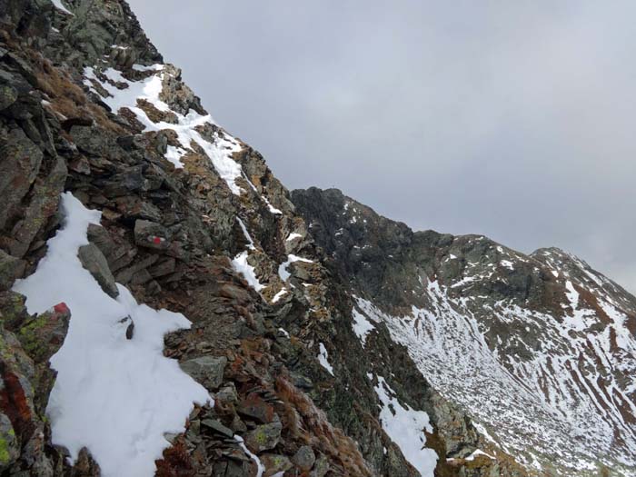 in Bildmitte erkennt man das Gipfelkreuz, rechts hinten die Barbaraspitze; auf den schmalen Bändchen und Rampen zum Vorgipfel immer wieder eingelagerte Schneeschilder, die in diesem absturzgefährdeten Gelände Vorsicht und Zeit verlangen