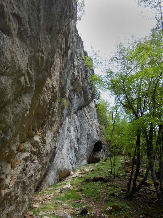 eine steile Wand mit abschließender Höhle, rechts oben zaghaft sprießende Infrastruktur in Form eines ... 