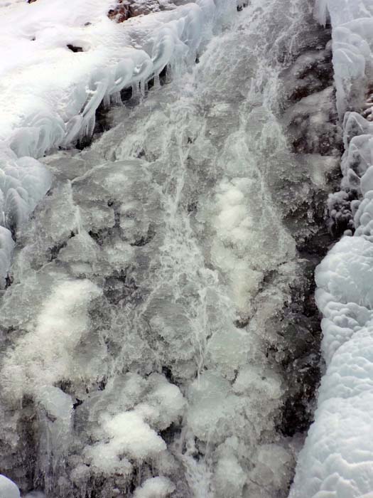 die erste Holzbrücke überspannt einen gefrorenen Bachlauf, der sich direkt unterhalb in einem Eisfall von beträchtlicher Höhe fortsetzt