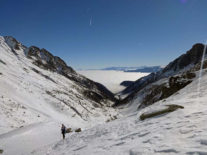 Rückblick ins nebelverhangene Drautal, darüber die Julischen Alpen; wenn es die Schneeverhältnisse zulassen, kann man am Ende der Wandabbrüche von der Rossalm über steilere Hangpartien abkürzen