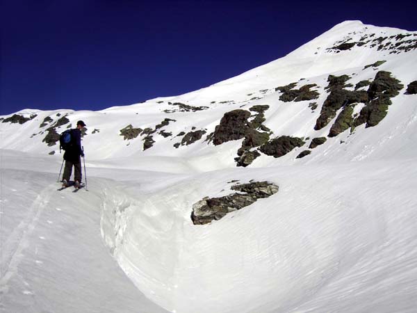 über eine kurze Stufe links hinauf zur Wildlochscharte; der elegante Firnhöcker ist erst das Schidepot, dahinter verbirgt sich der schneidige Südgrat auf unseren Gipfel