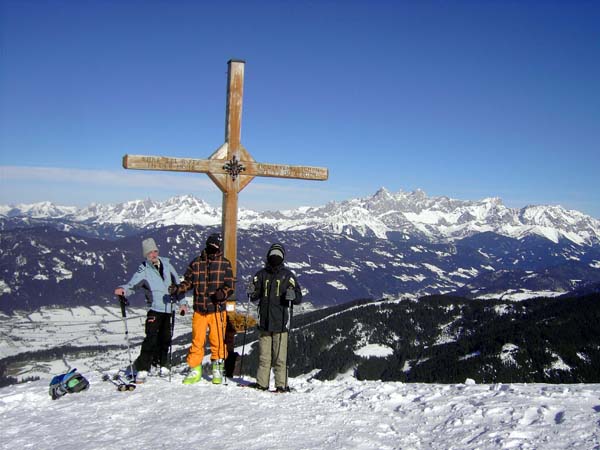 windgebeutelter Vater mit 2 strammen Söhnen am Gipfel; rechts des Kreuzes der Dachstein, links Gosaukamm