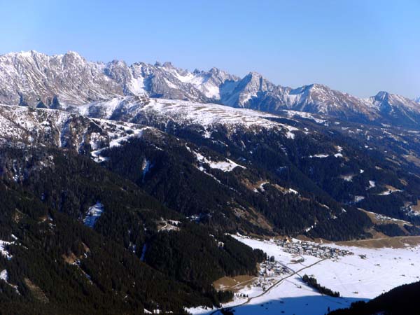 Gipfelblick nach NO auf den seit 1978 denkmalgeschützten Ort Obertilliach; die scharfe Kette der Lienzer Dolomiten läuft ganz rechts mit den sanfteren Schibergen Riebenkofel und Lumkofel aus
